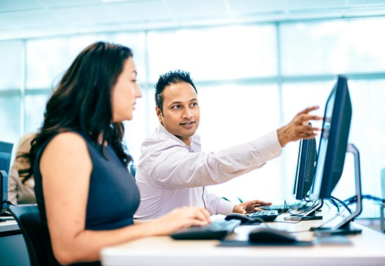 Employee providing customer training next to customer on computer